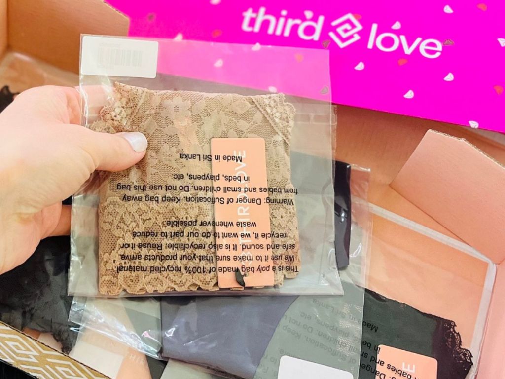 Box with Third Love Underwear inside with hand holding up a pair in plastic packaging