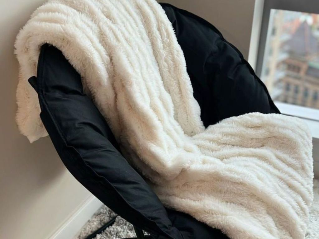 A faux rabbit fur blanket on a black chair