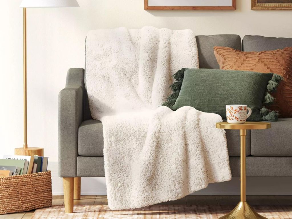 A white faux fur blanket on a grey couch 