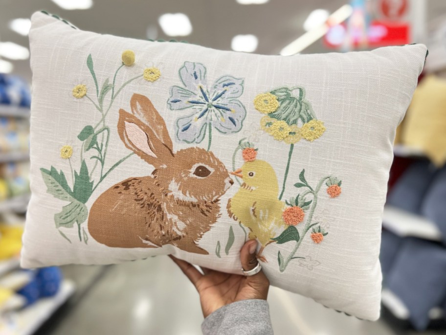 hand holding a white throw pillow with a brown bunny and yellow chick