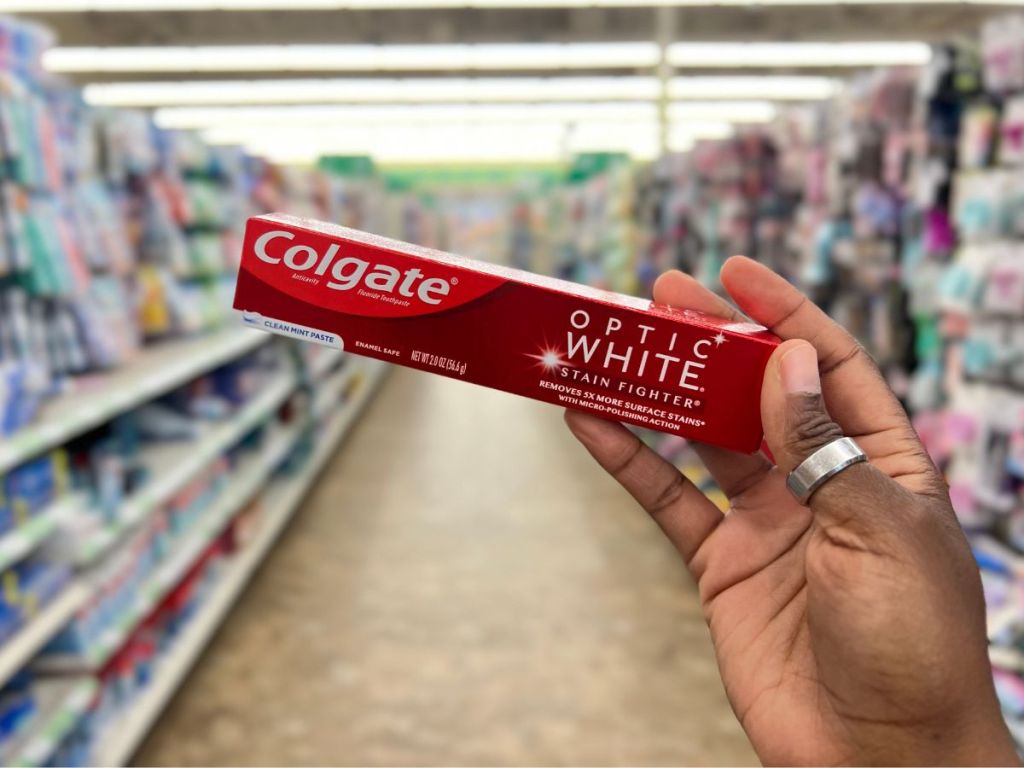 A hand holding a toothpaste box