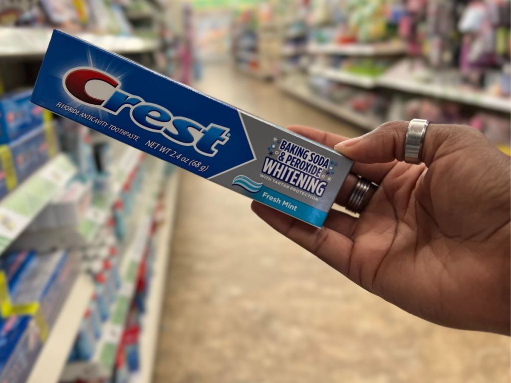 A hand holding a toothpaste box