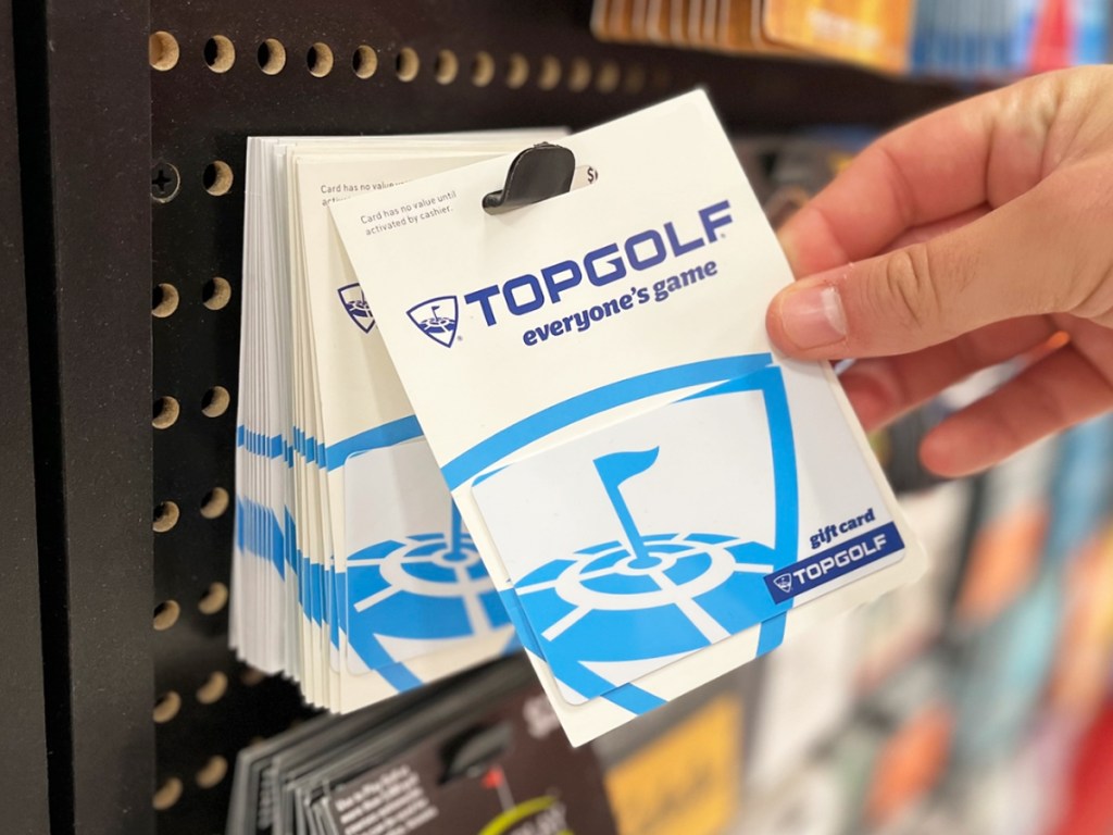 hand grabbing a topgolf gift card from store display