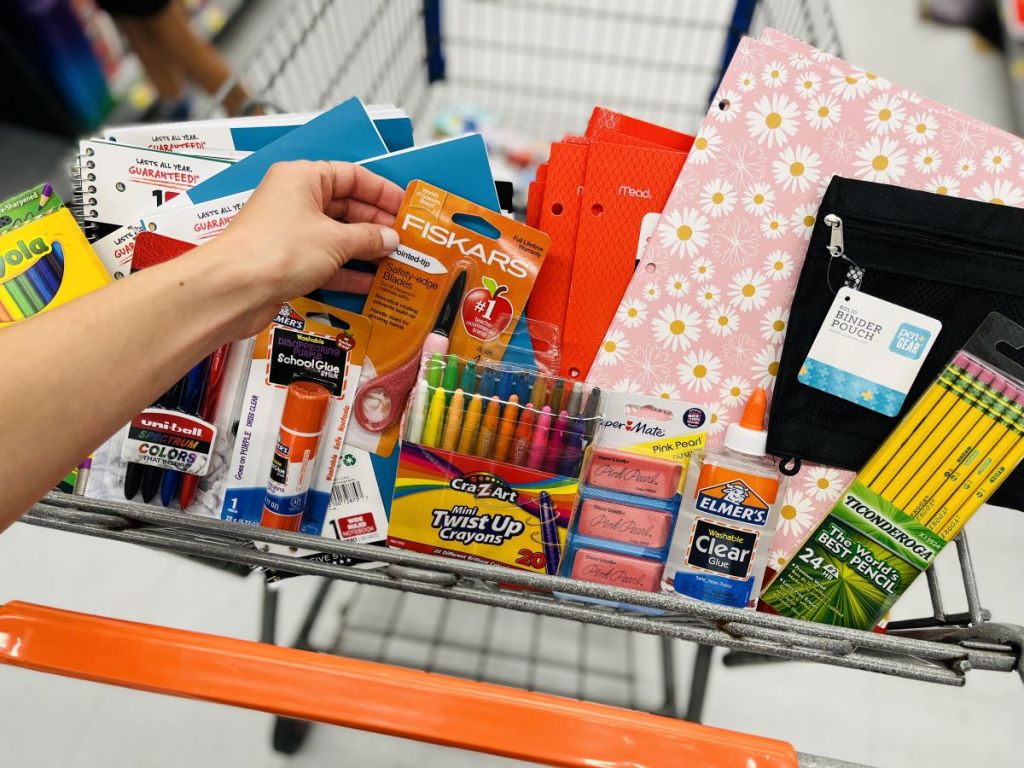 Hand grabbing school supplies in a Walmart cart