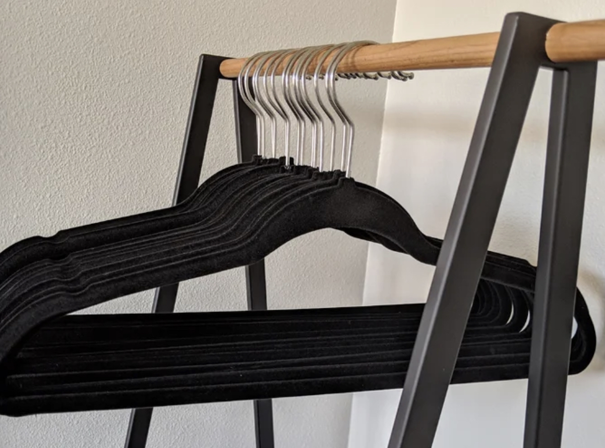 black velvet hangers hanging on wood clothes rack 