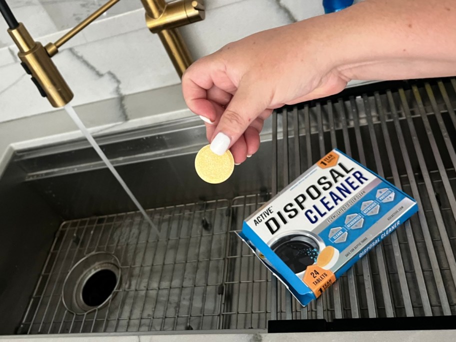 hand holding disposal cleaning tablet over sink