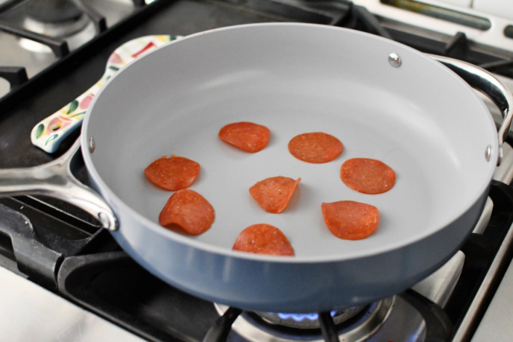 adding pepperoni to skillet