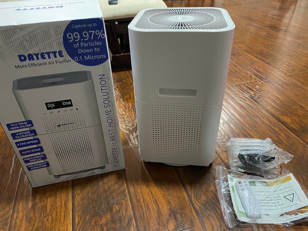 air purifier displayed opened outside of its box with remote control on the side