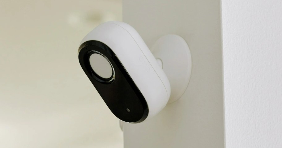 a white and black indoor security camera up on a wall