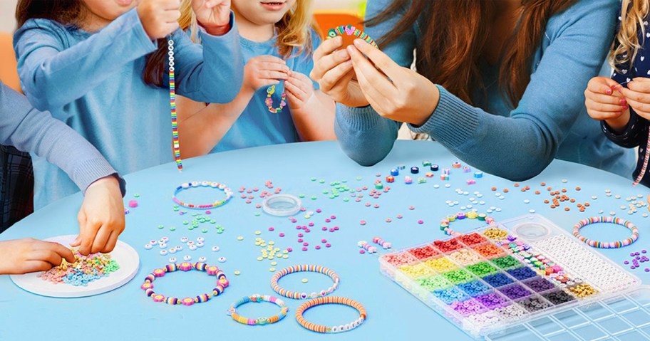 woman and kids making bracelets with beads on table