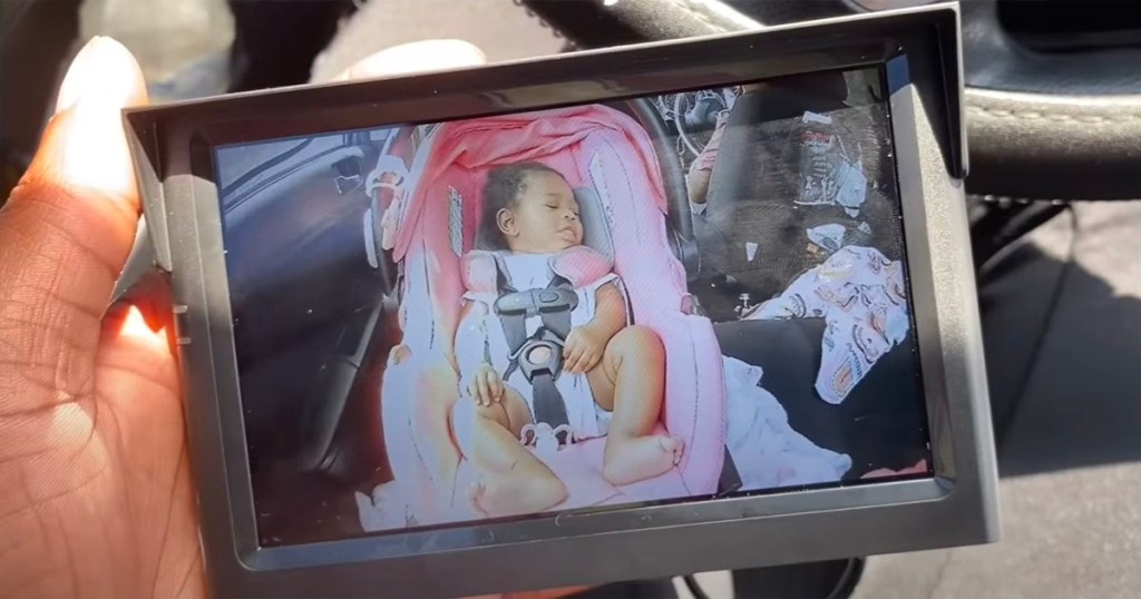 hand holding baby car camera with baby on screen