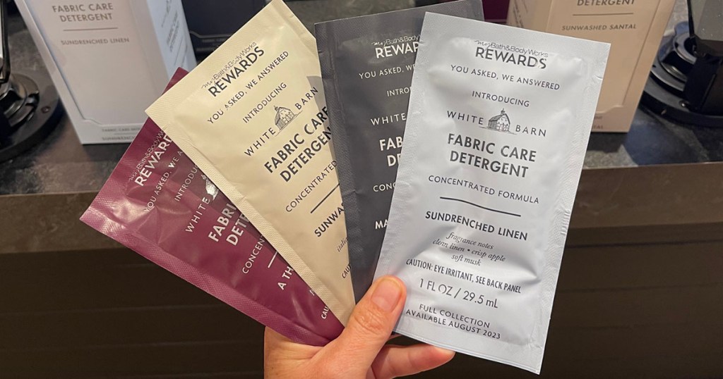 hand holding four laundry detergent samples 