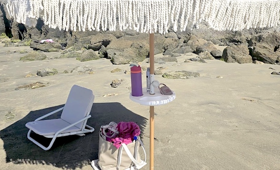 beach umbrella with tray in sand with white beach chair and bag 