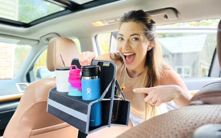 woman holding cup holder leaning into car with water bottles inside