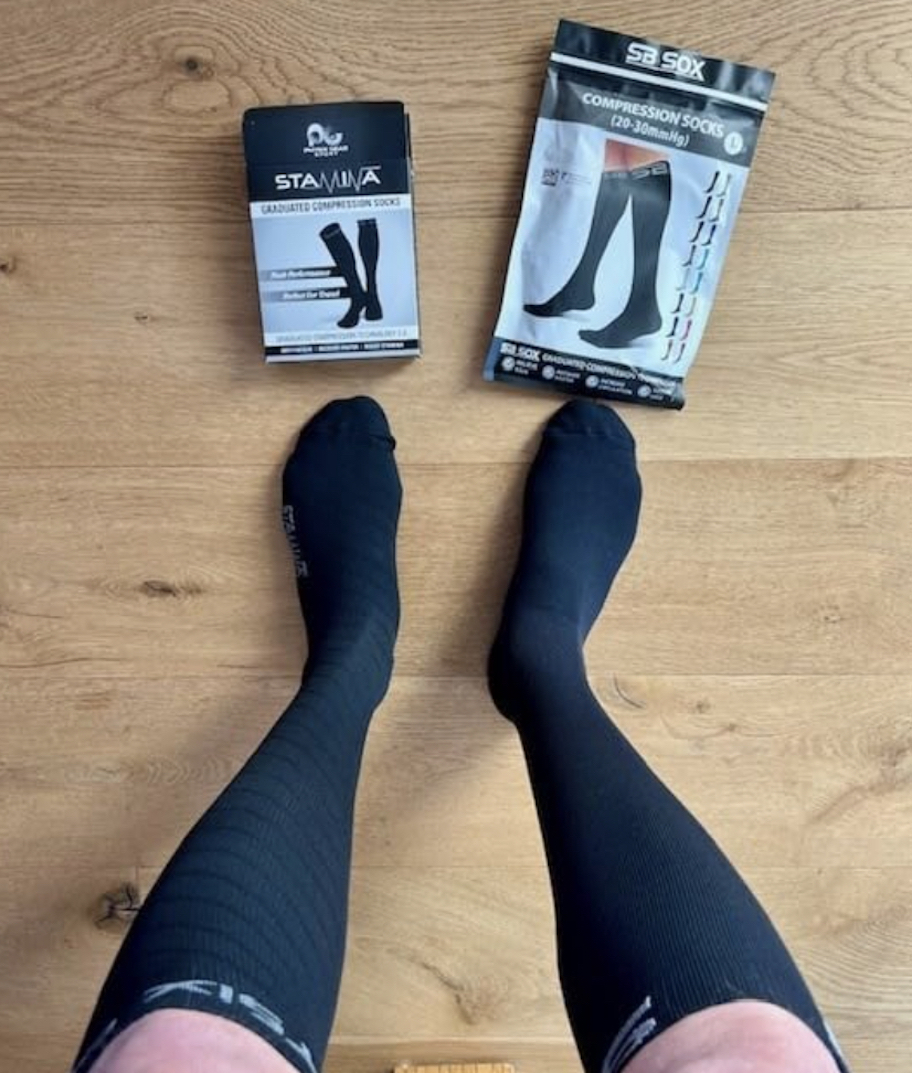 legs with black compression socks and packaging on wood floor