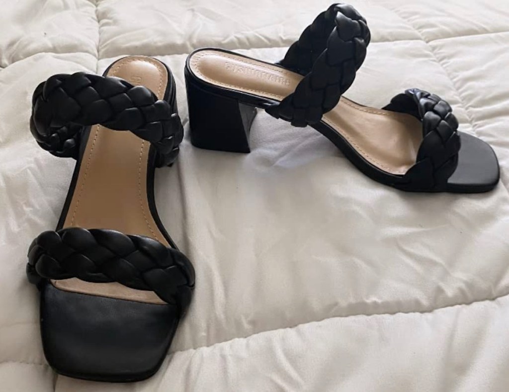 black slip on heels sitting on white duvet