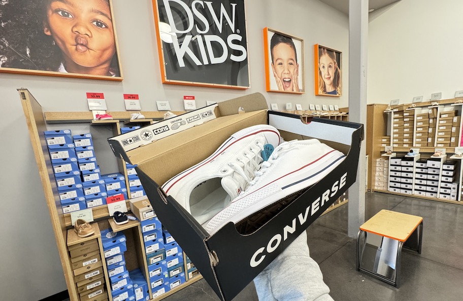 hand holding a box of converse sneakers in dsw kids section