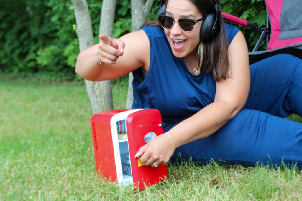 woman in grass with red mini fridge