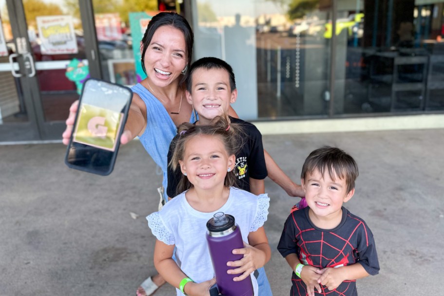 woman and children holding out phone with get out pass app