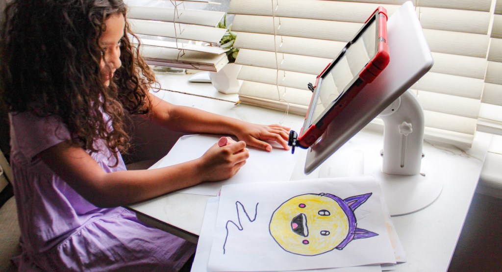 girl sitting on desk using her lap desk stand as she draws