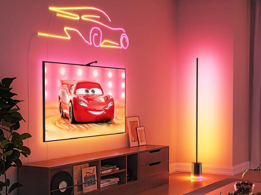 govee LED lamp lit up red and yellow next to a TV displaying an image of a red car