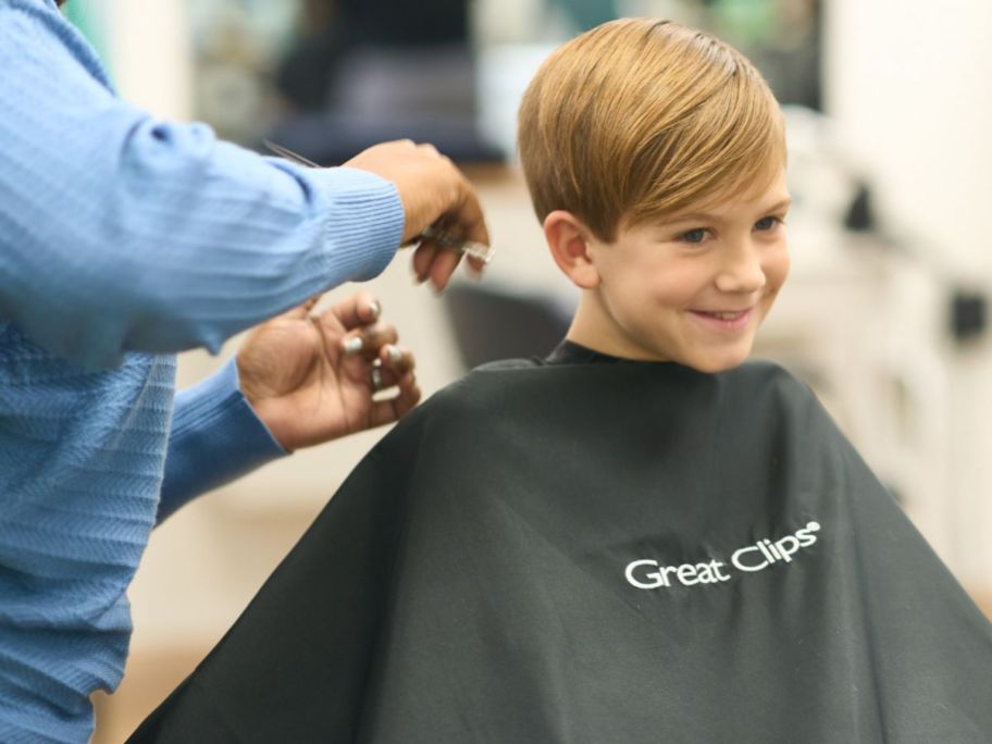 boy wearing great clips cape getting hair cut