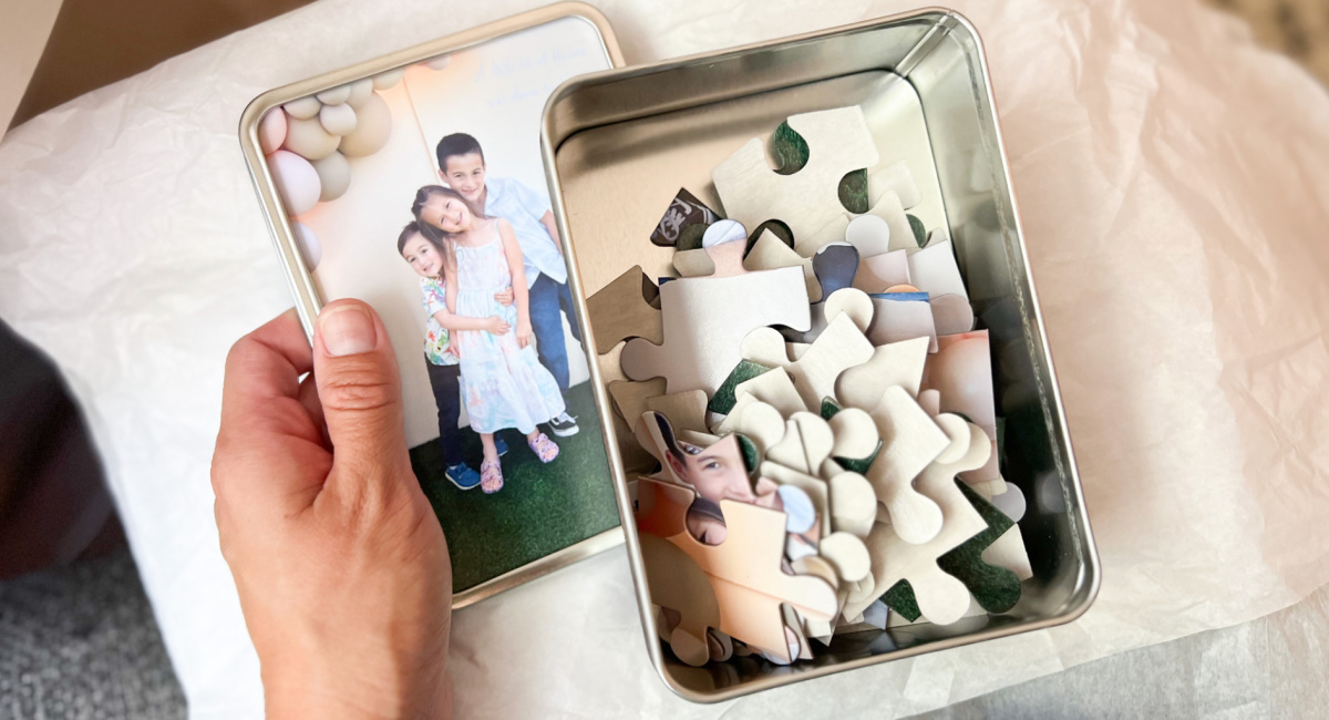 hand holding Walgreens photo puzzle keepsake with tin and puzzle inside
