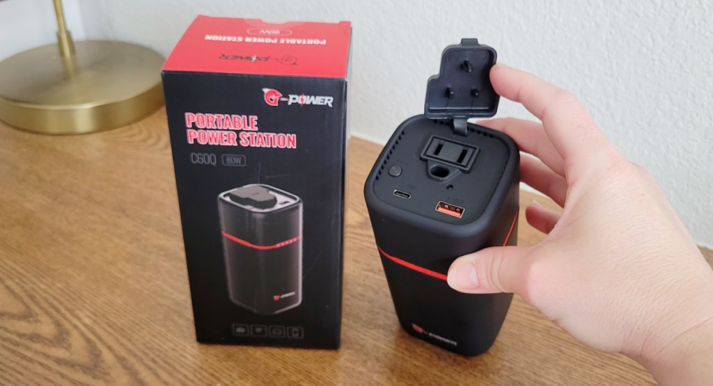 hand holding portable power bank next to its box on the table