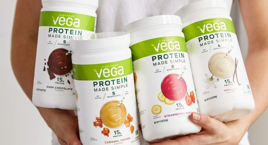 hand hugging bottles VEGA protein in four different flavors