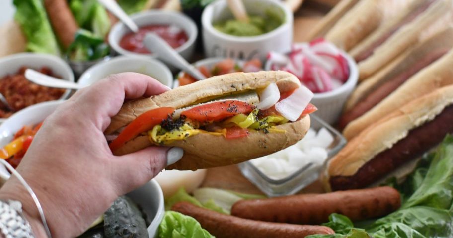 hand holding chicsgo style hot dog above hot dog ingredients
