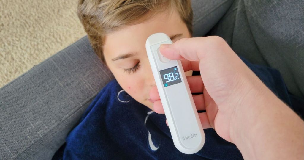 person using thermometer near boys forehead