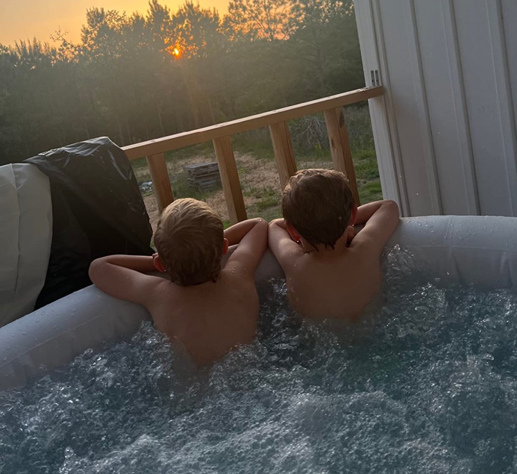 two kids looking at sunset in inflatable hot tub
