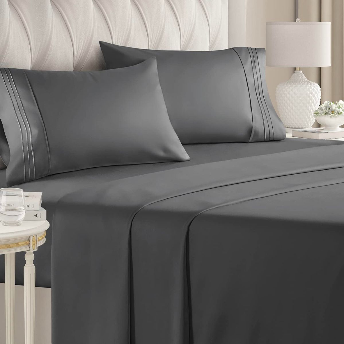 dark gray sheet set on a bed with a quilted grey velvet headboard 