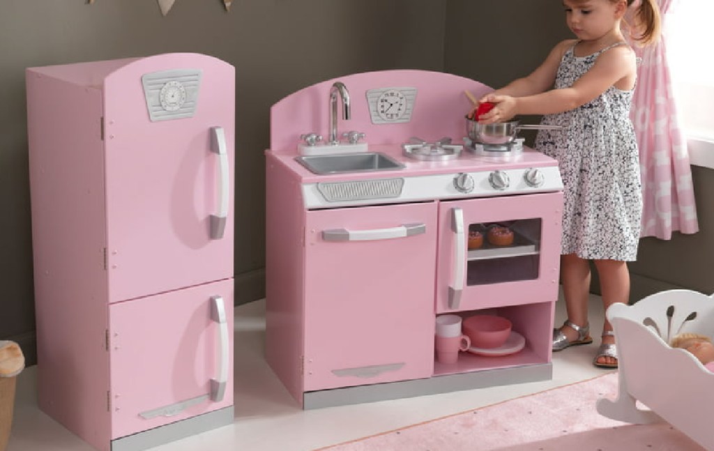 little girl playing with her kitchen and fridge set