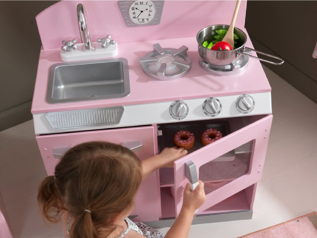 little girl playing with her pink kitchen