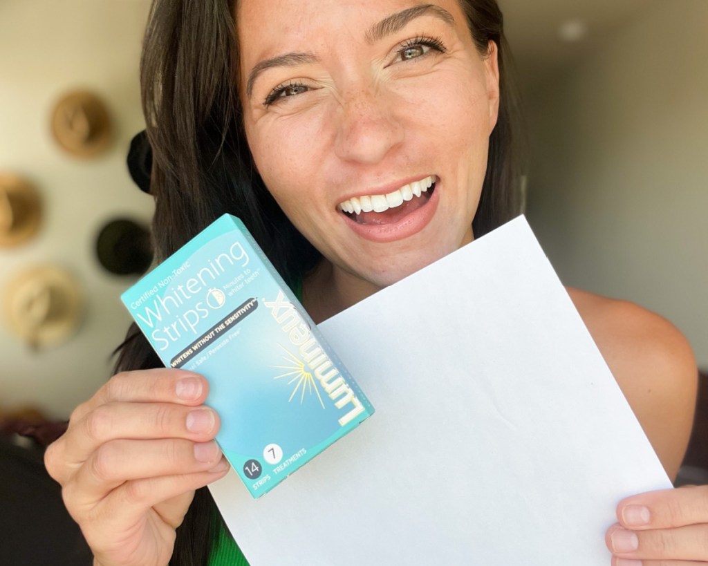 woman holding piece of paper and whitening strips box