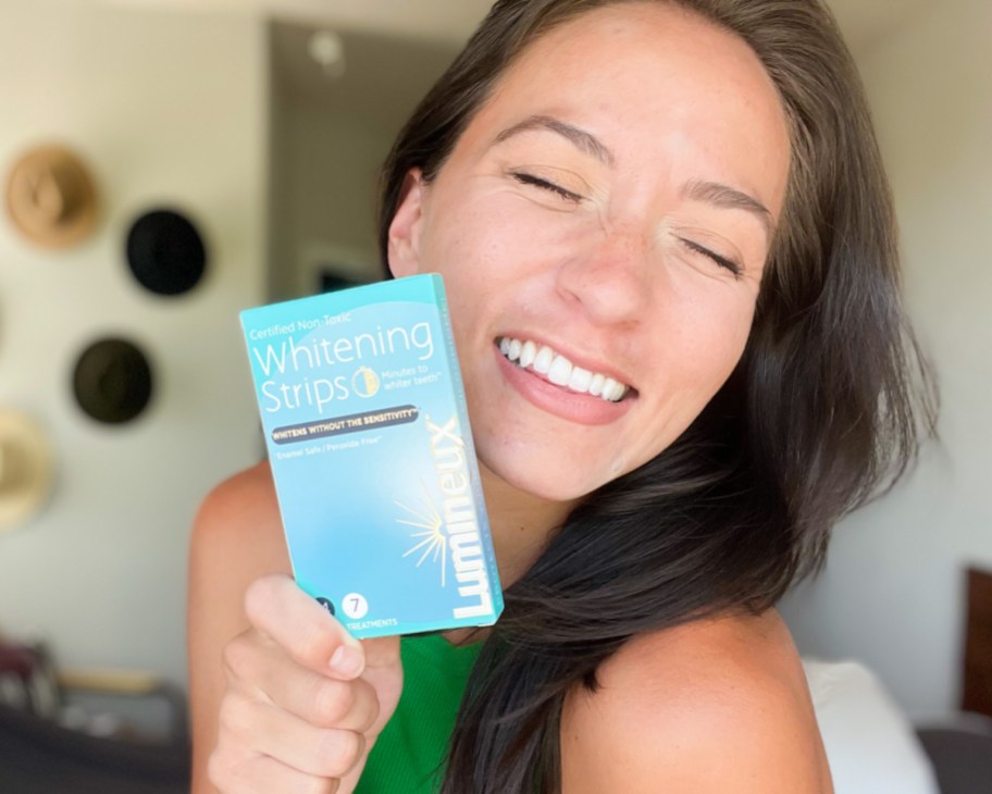 woman smiling while holding a blue box of whitestrips