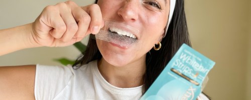 woman holding whitening strips over teeth