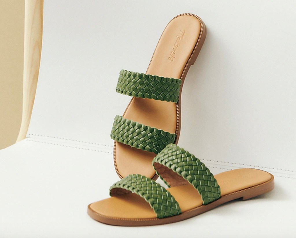 green and tan leather slides leaning on white chair