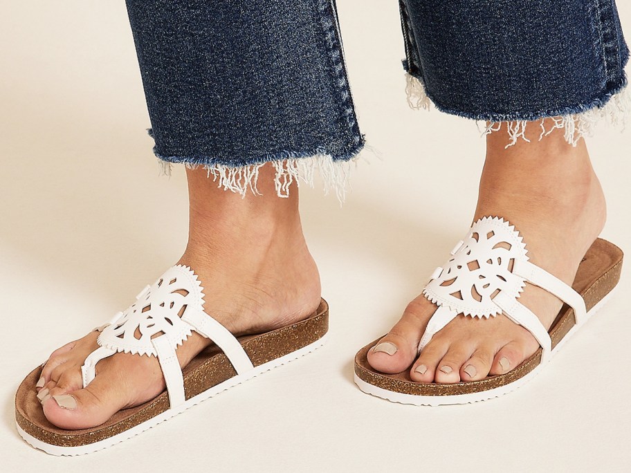 woman wearing pair of white sandals and jeans