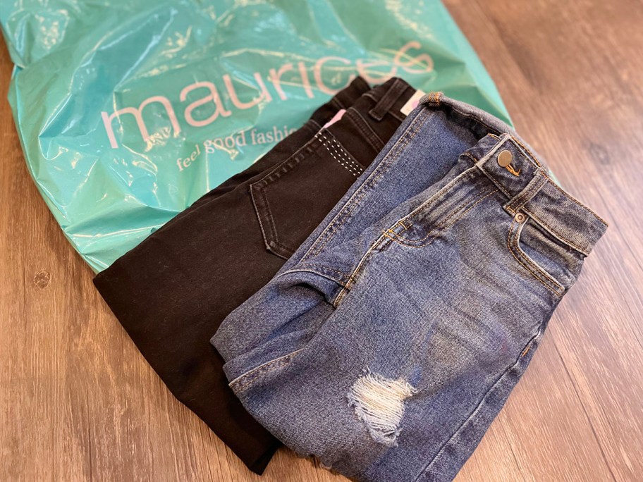 teal maurices bag with two pairs of kids jeans folded on top of it