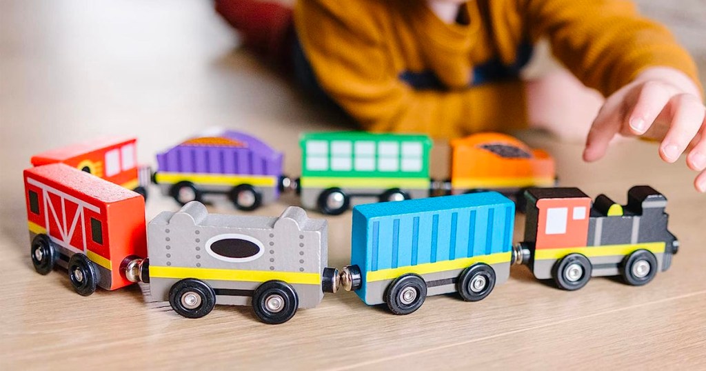 boy playing with 8 piece wooden train set toy