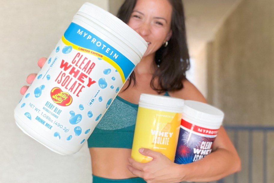 woman holding many protein tubs