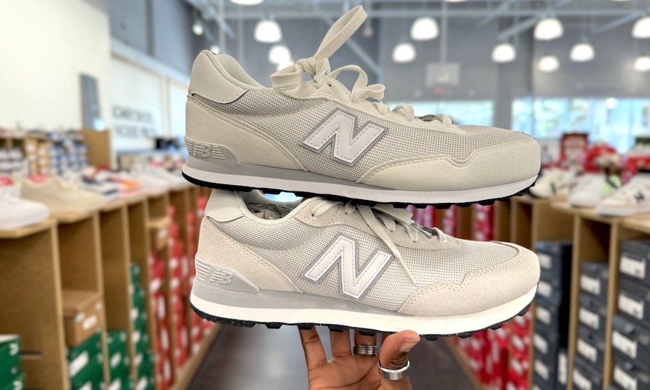 hand holding two slightly different New Balance shoes
