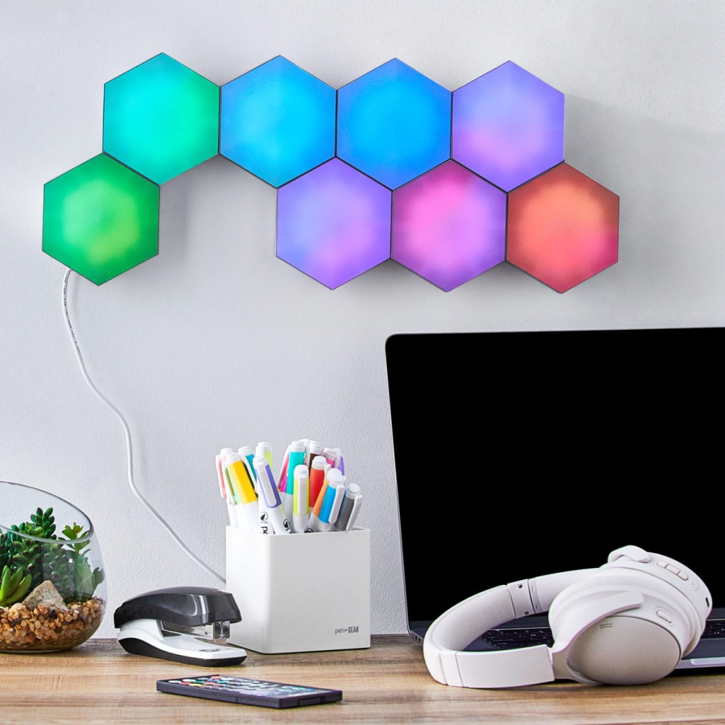 colorful hexagon light panels illuminated and displayed on the wall behind a computer screen and desk