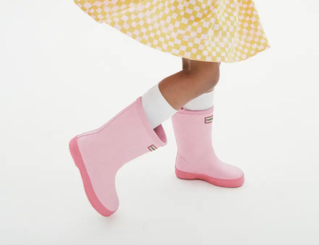 close up of kid jumping around in pink hunter rain boots