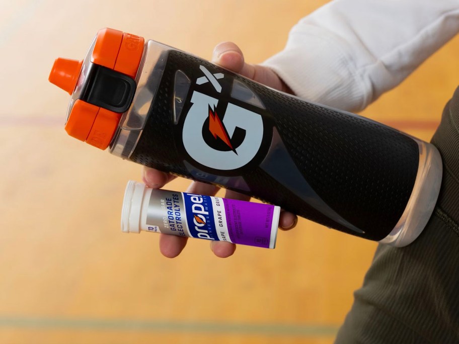 hand holding gatorade bottle and propel tablets