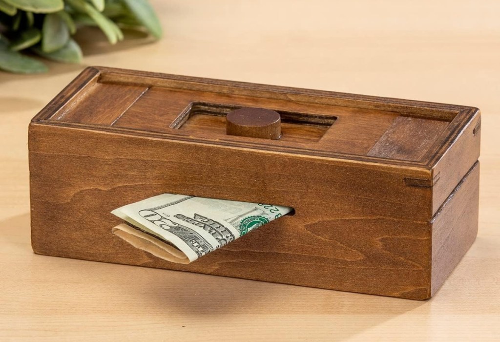 wooden puzzle box showing money being inserted