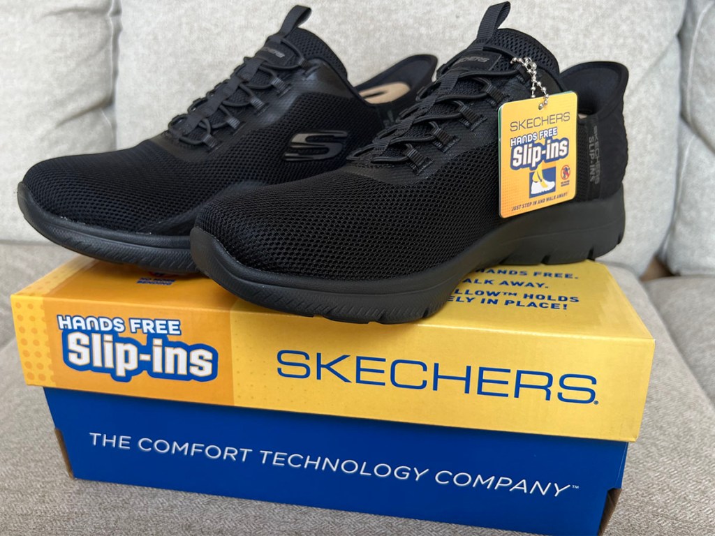Black setchers shoes on box on couch