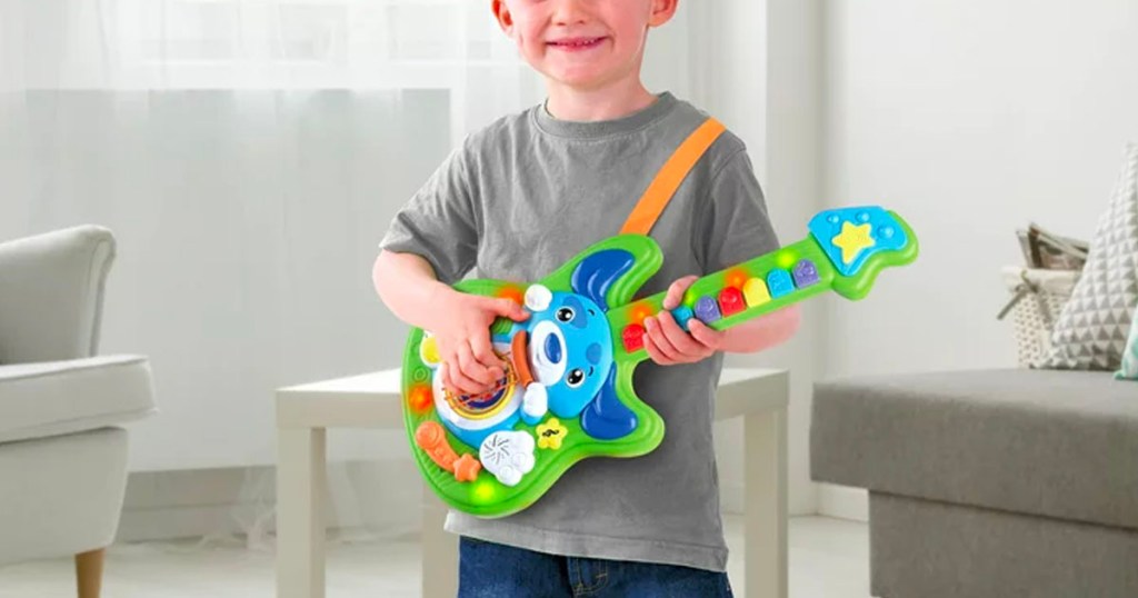 boy playing with green and blue puppy guitar